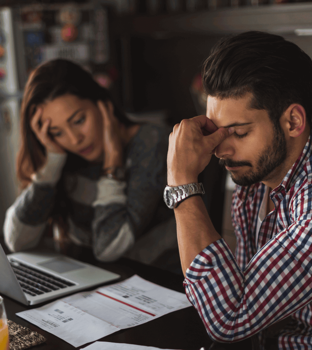 Stressed couple sitting at a table with bills